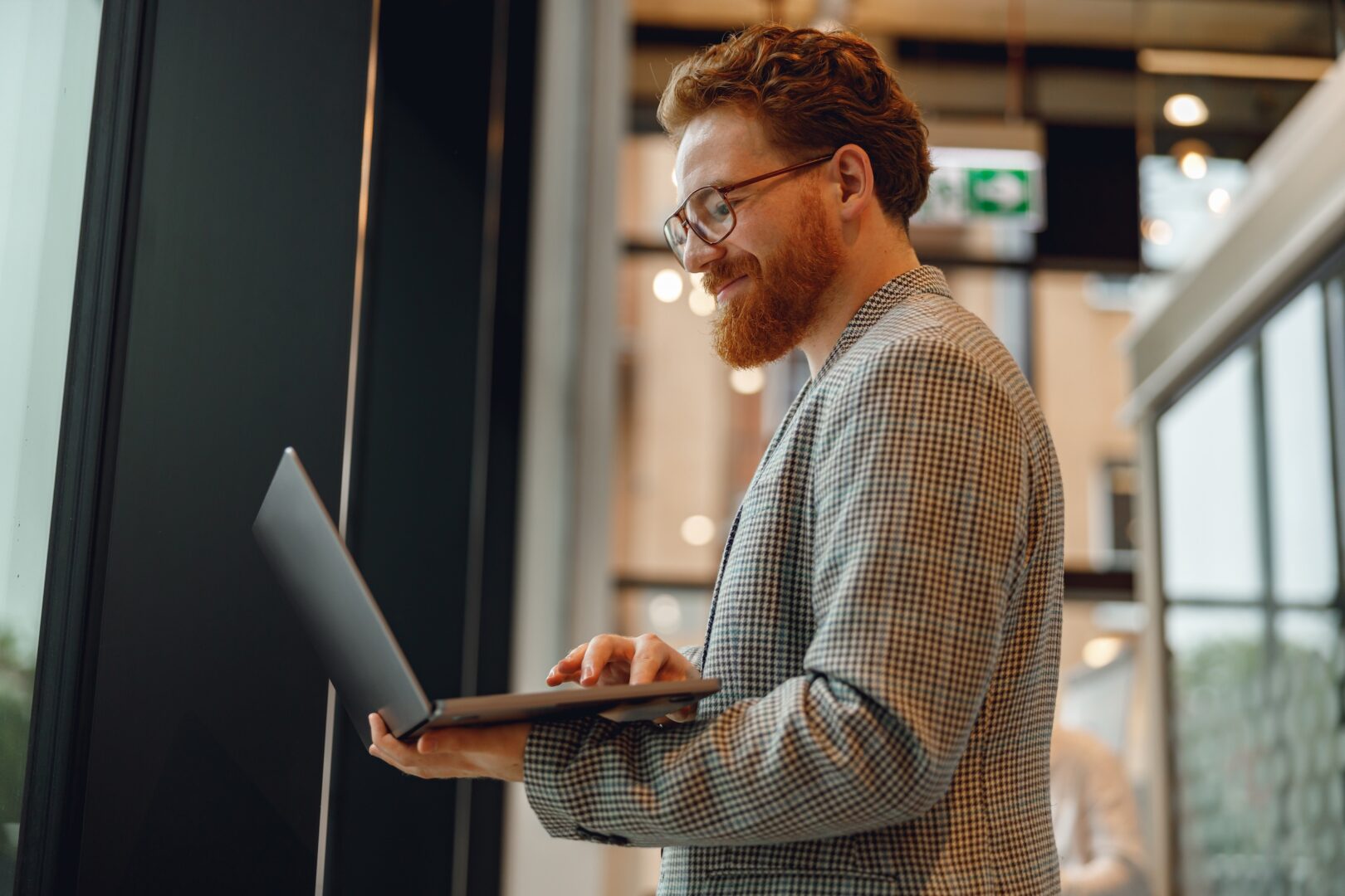 Handsome sales manager with laptop standing on modern coworking background